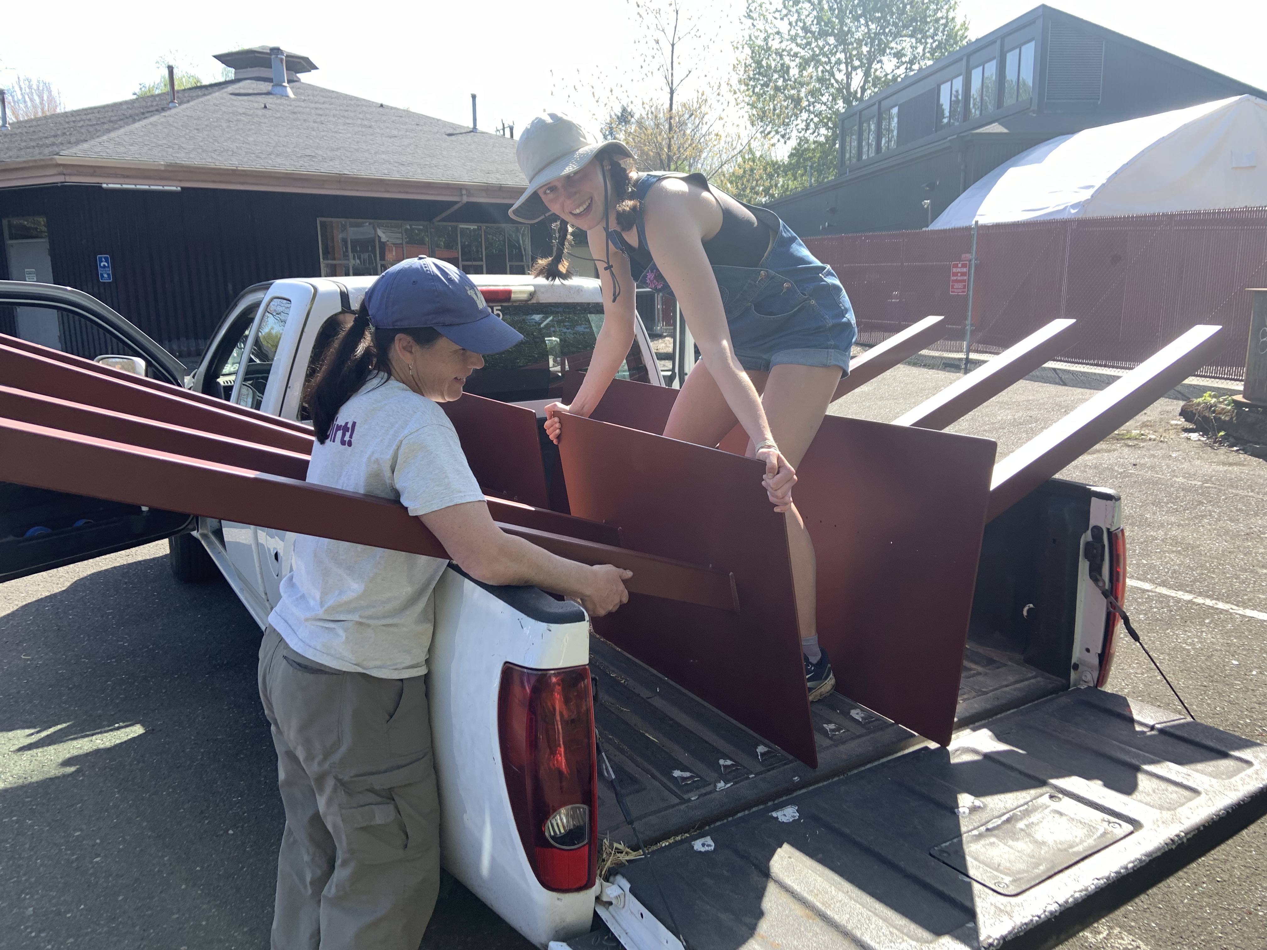 Two farm workers load steel signposts into a truck